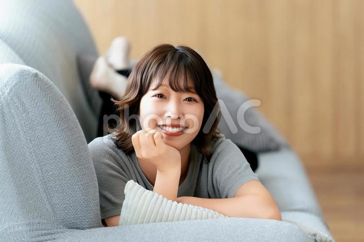 ソファに寝転ぶ笑顔の女性 女性,ソファ,笑顔の写真素材