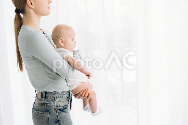 窓際で赤ちゃんを抱いている女性 親子,母子,赤ちゃんの写真素材