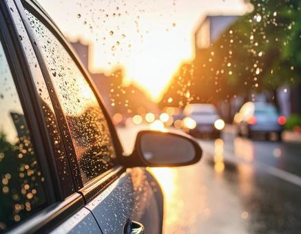夕立ちに照らされる車と雨の写真
