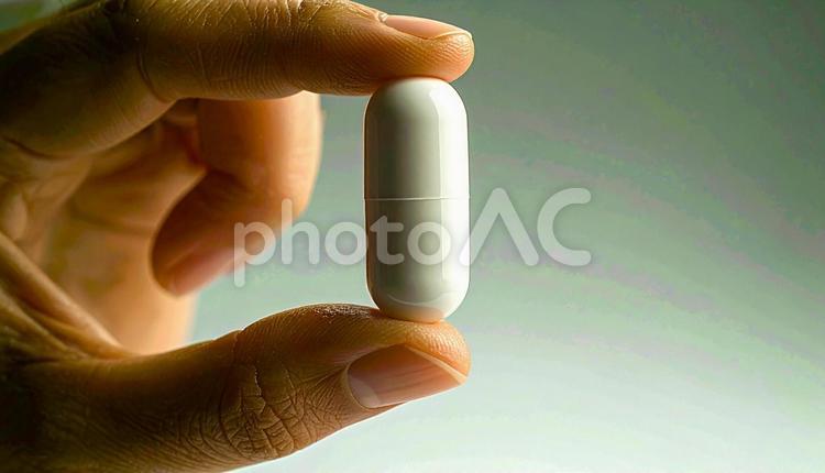 薬一錠を親指と人差し指で持つ手 カプセル,手,医療の写真素材