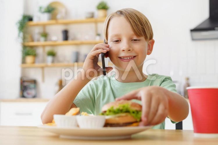 ハンバーガーを掴んで電話する男の子 男の子,人物,飲むの写真素材