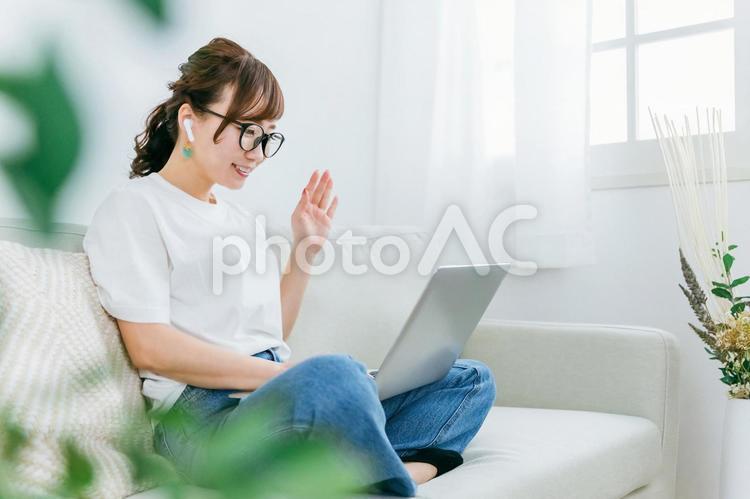 パソコンでテレワークして挨拶する女性 テレワーク,リモートワーク,英会話の写真素材