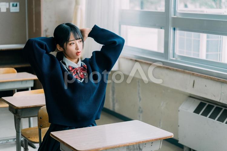 教室の窓際で髪を束ねる女子高校生 女子高校生,高校生,学生の写真素材