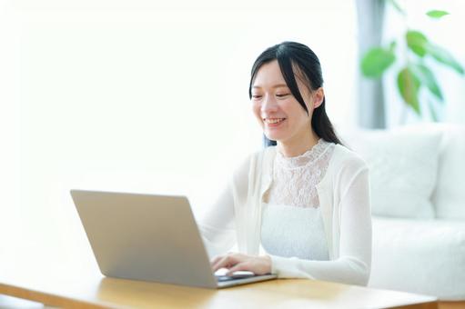 パソコンを操作しながら笑っている女性 女性,ノートパソコン,見るの写真素材