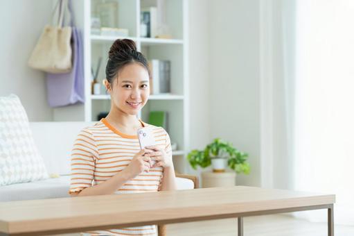 リビングでスマホを見る若い女性 リビングでスマホを見る若い女性の写真