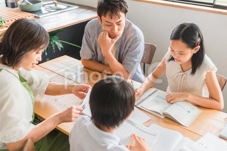 家で宿題をする子供達と手伝う両親 宿題,勉強,家族の写真素材