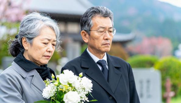 お葬式・墓参りで目頭をおさえる老夫婦 お葬式・墓参りで目頭をおさえる老夫婦の写真