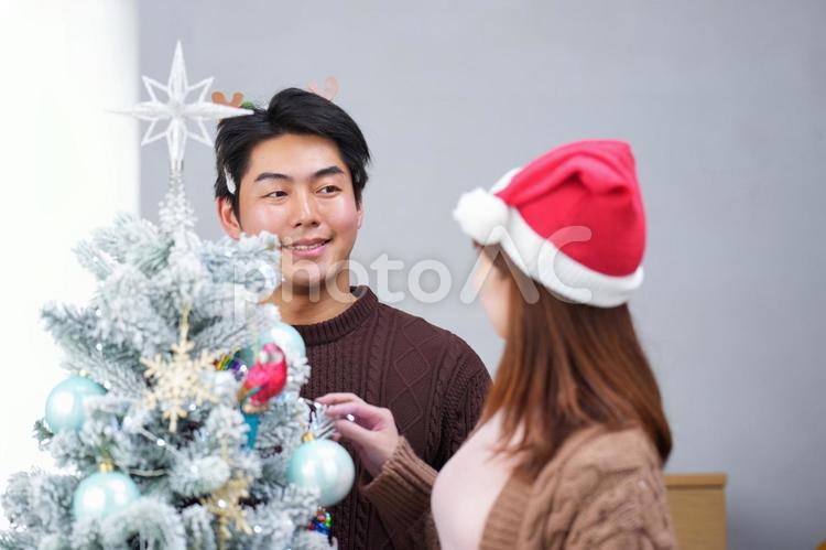 話しながらクリスマスツリーを飾り付けする夫婦 夫婦,女性,男性の写真素材