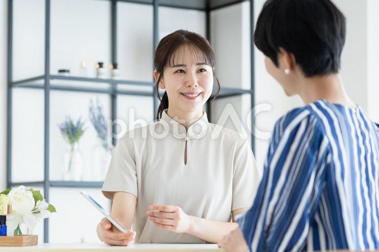 若い女性の接客をするサロンのスタッフ マッサージ,サロン,受付の写真素材