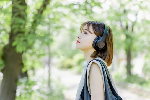 新緑の中ヘッドフォンで音楽を聴く若い女性 新緑の中ヘッドフォンで音楽を聴く若い女性 女性,人物,ヘッドフォンの写真素材