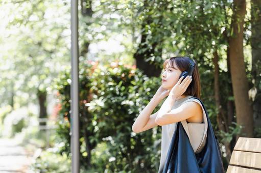 新緑の中ヘッドフォンで音楽を聴く若い女性 新緑の中ヘッドフォンで音楽を聴く若い女性 女性,人物,ヘッドフォンの写真素材