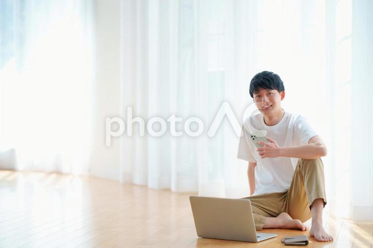 床に座ってノートパソコンとスマートフォンを使う男性 男性,お父さん,大人の写真素材