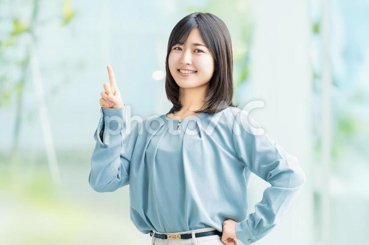 人差し指を立てて案内する笑顔の女性 女性,指,笑顔の写真素材