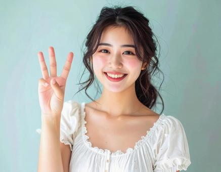 3を指で示す笑顔の女性 3を指で示す笑顔の女性の写真