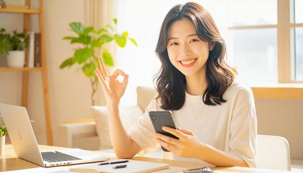 家計がうまくいきスマホ片手に微笑む女性 家計がうまくいきスマホ片手に微笑む女性の写真