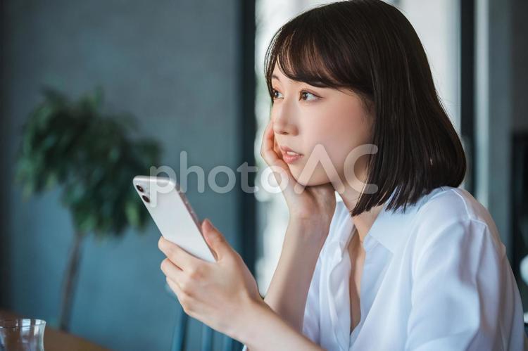 スマホを見て考える若いビジネスウーマン 女性,ビジネス,ビジネスウーマンの写真素材