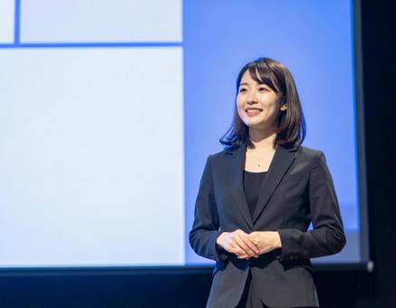 ステージ上でプレゼンをする女性 ステージ上でプレゼンをする女性の写真
