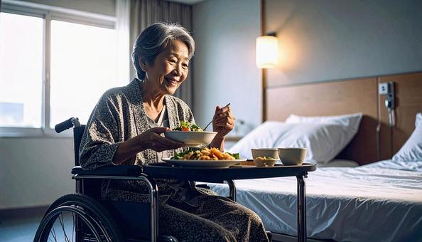 病室で車いすに座り食事をする高齢女性患者の写真