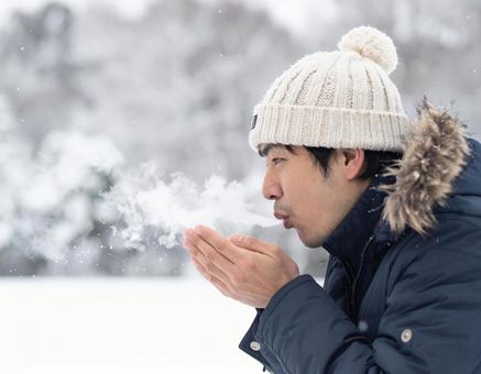 冬に手に息を吹きかける男性 冬に手に息を吹きかける男性の写真