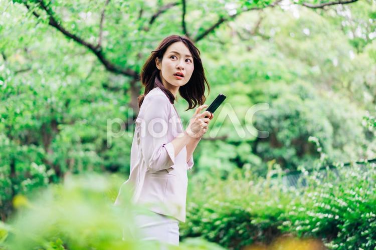 外でスマホを使うビジネスウーマン スマホ,公園,屋外の写真素材