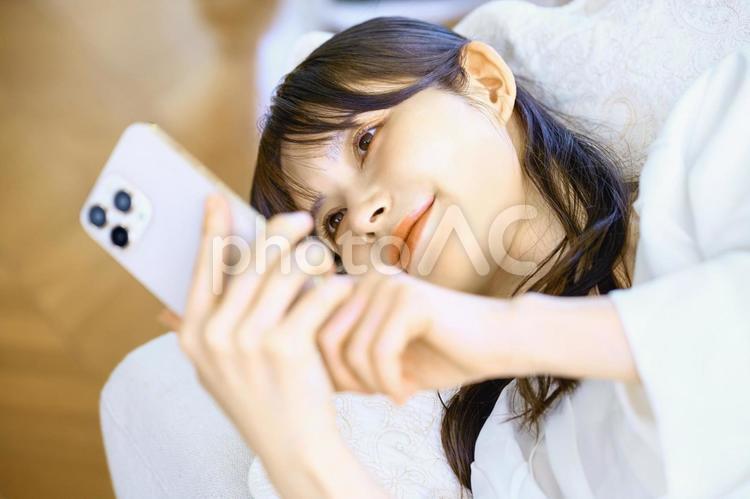 寝転んでスマホを見る女性　主婦　仰向け スマホ,女性,主婦の写真素材