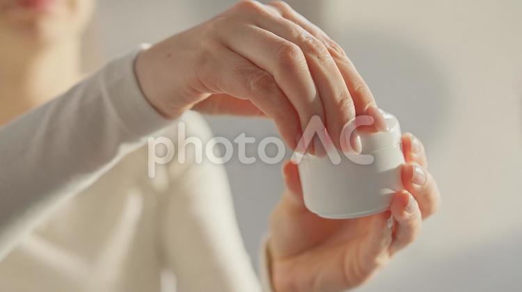 クリーム容器の蓋を開ける女性の上半身 女性,外国人,1人の写真素材