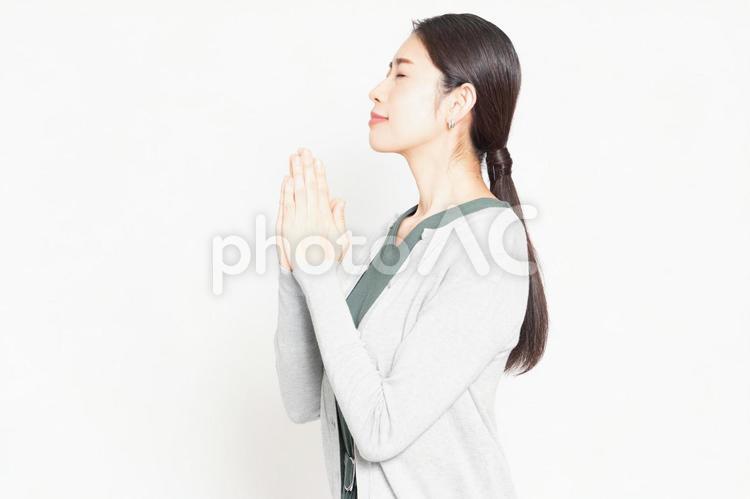 白背景の前で、お願いのポーズをする女性 主婦,お願い,女性の写真素材