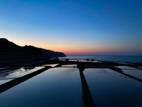 鏡のような水田に映る海と夕暮れ 鏡のような水田に映る海と夕暮れ 水田,鏡面,海辺の写真素材