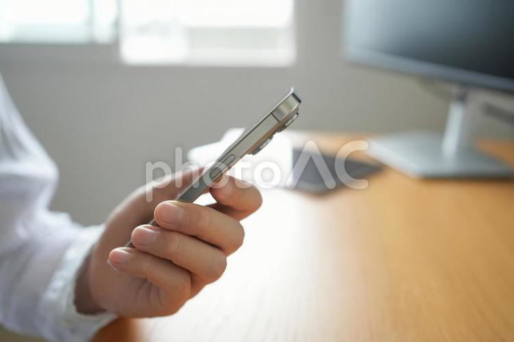 おしゃれオフィスでスマートフォンを持つ手 スマートフォン,スマホ,手の写真素材