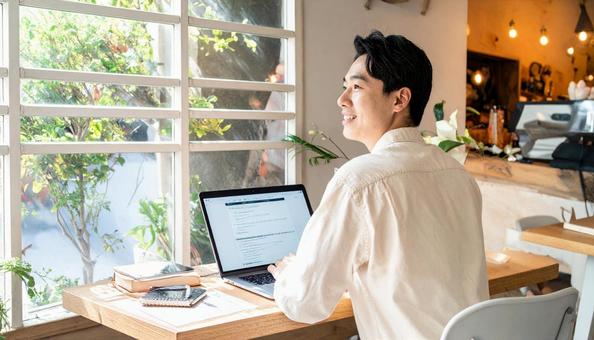 カフェで仕事をするフリーランス男性 カフェで仕事をするフリーランス男性の写真