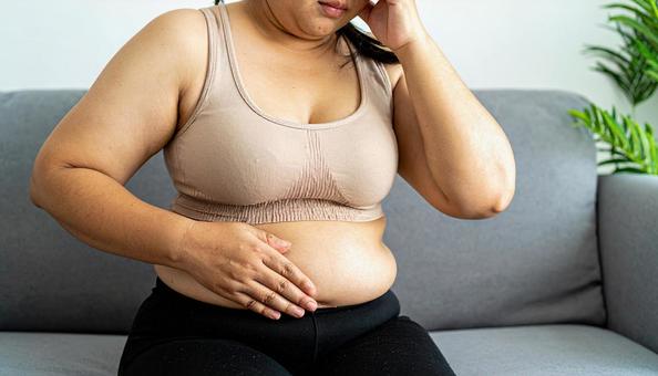 肥満で疲れやすく、額に手をやる女性 肥満で疲れやすく、額に手をやる女性の写真