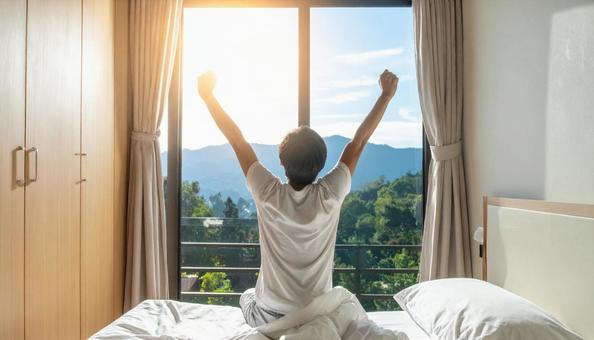 寝室で良質な睡眠・熟睡して起きる男性の写真