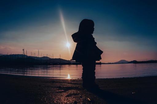 夕暮れ時の海辺を散歩する子供のシルエット 夕暮れ時の海辺を散歩する子供のシルエット 子供,海岸,秋の写真素材