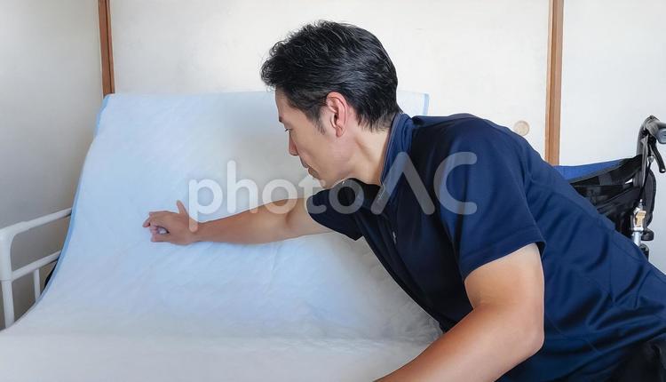 電動ベットのシーツを伸ばす介護スタッフ 介護福祉士,福祉,介護士の写真素材