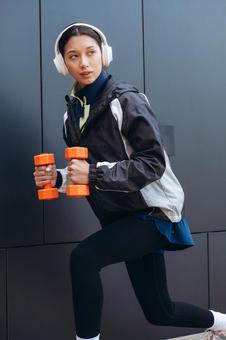 ダンベルで筋トレしながらチラ見する女性 ダンベルで筋トレしながらチラ見する女性の写真