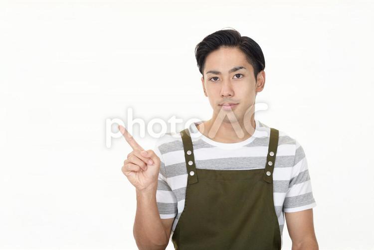 指さすエプロン姿の男性 男性,家事,案内の写真素材