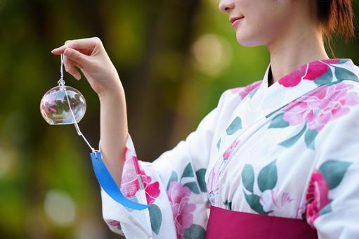 浴衣姿の女性が屋外で風鈴を掲げる 風鈴,持つ,浴衣の写真素材