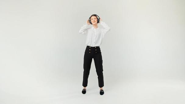 目を瞑りヘッドホンを押さえる女性 目を瞑りヘッドホンを押さえる女性の写真