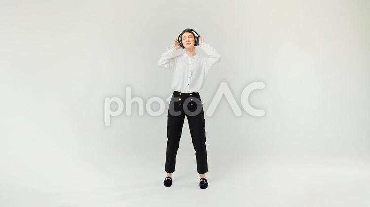 目を瞑りヘッドホンを押さえる女性 女性,ヘッドホン,聴くの写真素材