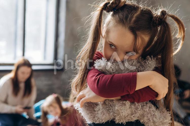 ぬいぐるみを抱きしめてチラ見する女の子 女性,女の子,人物の写真素材