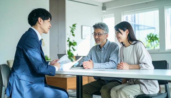 男性営業マンの説明を聞く夫婦 男性営業マンの説明を聞く夫婦の写真
