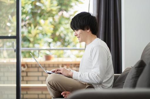 A man using a computer in his living room, laptop, male, living, JPG