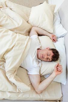 ベッドで両手を上げて寝ている男性 縦,男性,外国人の写真素材