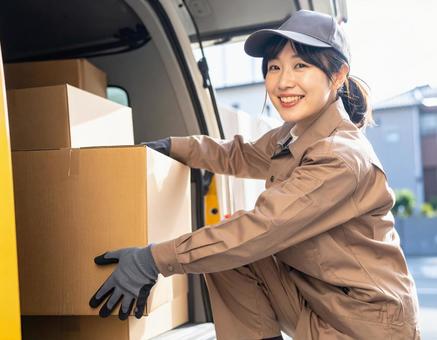 トラックから荷物を出す宅配女性ドライバー トラックから荷物を出す宅配女性ドライバーの写真