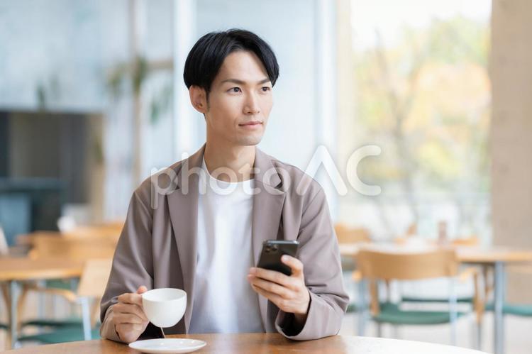 カフェでくつろぐ若い男性 カフェ,男性,カフェテリアの写真素材