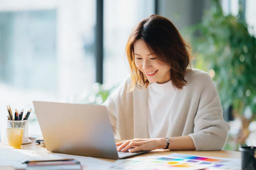 ノートパソコンを使って作業する若い女性 ノートパソコンを使って作業する若い女性の写真