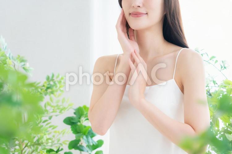 緑の中でスキンケアをする若い女性 ビューティー,女性,スキンケアの写真素材