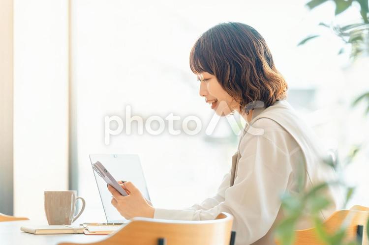 スマホを使う笑顔の女性・ビジネスウーマン 女性,ビジネス,ビジネスウーマンの写真素材