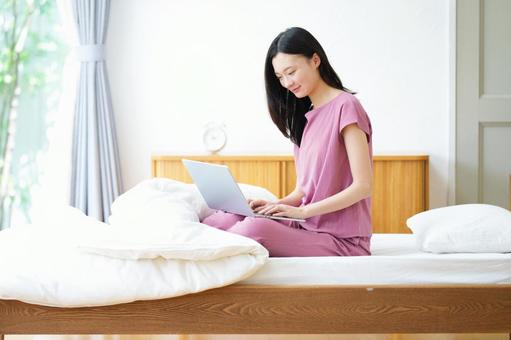 ベッドに座りパソコンをしている日本人女性 女性,ノートパソコン,ベッドの写真素材