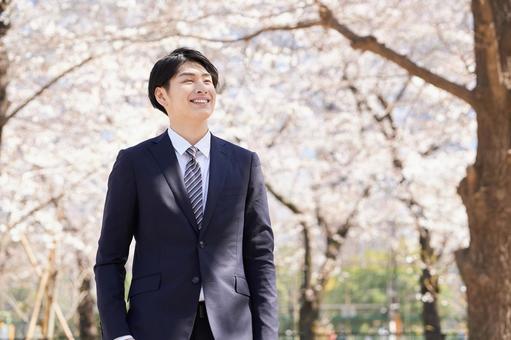 Japanese male businessman standing with a smile against the background of cherry blossoms, предприниматель, человек, улыбка, JPG